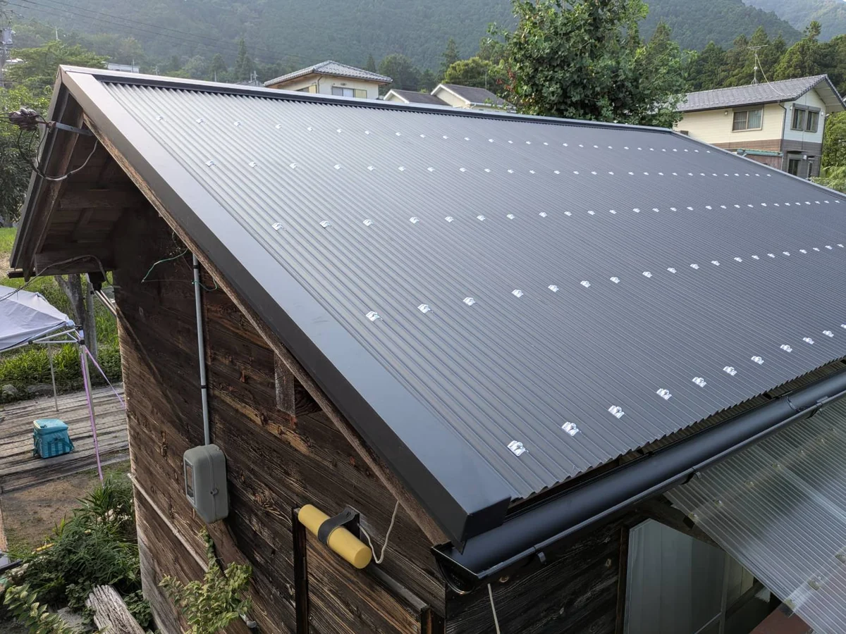 葺き直し後の納屋の屋根。新しい鉄板小波が張られ軒先も板金で納まった状態