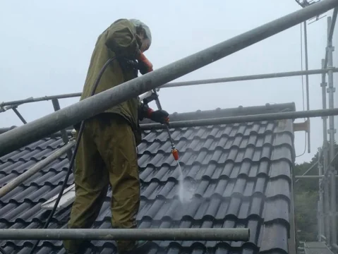 大屋根を高圧洗浄機で洗っているところ。瓦の汚れと苔を水圧で落としている